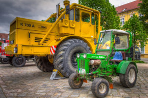 Große Landmaschine und kleiner Traktor auf dem Markt in Templin nebeneinander